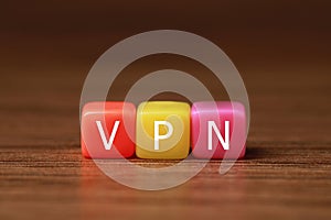 Colorful plastic beads with acronym VPN on wooden table