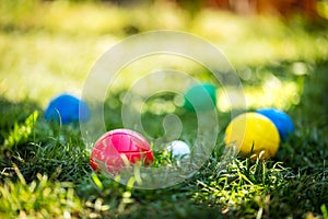 Colorful plastic boules or boccia balls are lying on a green meadow