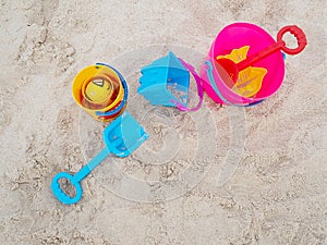 Colorful plastic children`s beach toys on sand beach in summer day. Kids toys, bucket, shovel