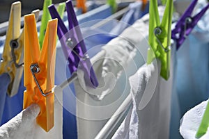 Colorful plastic clothes pegs on rack