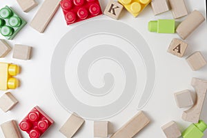 Colorful plastic construction blocks and wooden cubes on white background as kids toys frame. Flat lay. Top view