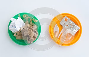 Colorful, plastic garbage plates. Plastic waste on one plate, and paper rubbish on another. Symbol of recycling, waste sorting and