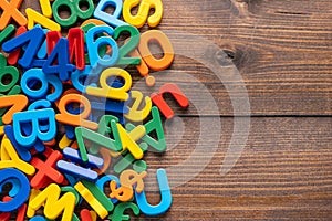 Colorful plastic letters and numbers on wooden background