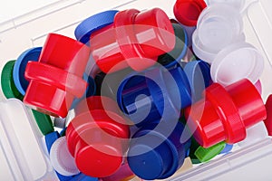 Colorful plastic lids in a box on white background