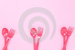 Colorful plastic spoon and fork on pink table backgroun