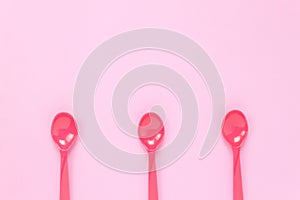 Colorful plastic spoon on pink table background with co