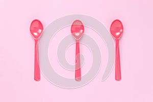 Colorful plastic spoon on pink table background with co