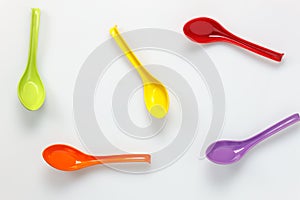 Colorful plastic spoon on white table background with c