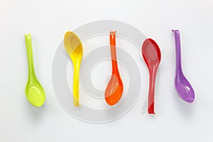 Colorful plastic spoon on white table background with c