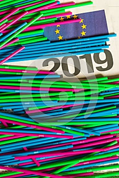 Colorful plastic straws on news paper sheet with 2019 and EU sign on it. ban act of plastic packaging in Europe 2019