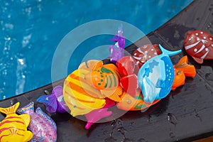 Colorful plastic toy fish in a blue pool with water for fishing by children