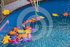 Colorful plastic toy fish in a blue pool with water for fishing by children