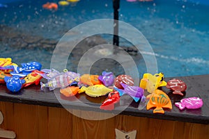 Colorful plastic toy fish in a blue pool with water for fishing by children