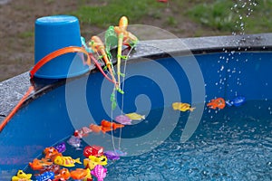 Colorful plastic toy fish in a blue pool with water for fishing by children