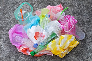 Colorful plastic waste, bags, cups, bottles, straws on cement floor
