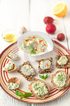 Colorful plate with different bread with tzatziki on the white table