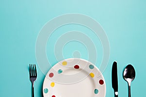 A colorful plate with fork and spoon on green background.