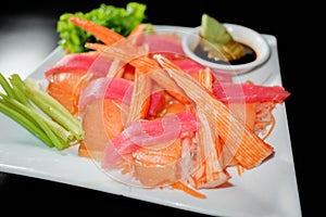 A colorful platter of sashimi sushi with tuna and crab sticks