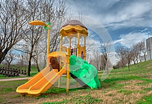 Colorful playground on green grass and walking path together with small wooden bridge