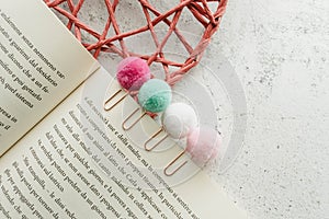 Colorful pom pon paper clips stationery - on a book page