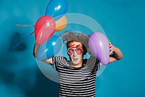 Colorful portrait of young funny man posing on blue wall