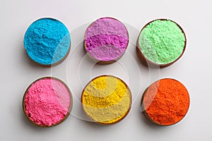 Colorful powders in bowls on light background, flat lay. Holi festival celebration