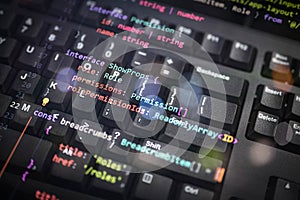 Colorful programming interface code overlay on black keyboard, showcasing software architecture, permissions, and user role