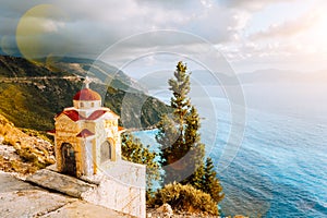 Colorful Proskinitari shrine lantern on pedestal on the cliff edge. Amazing coastline view with cloudscape in the