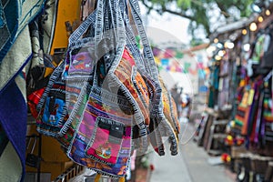 Colorful purses hang outside a shop