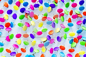 Colorful push pins on blue wooden background, close up.