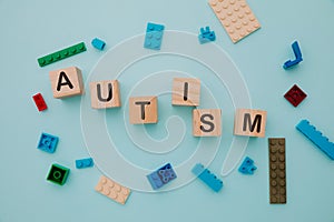 Colorful puzzle on a table and wooden blocks with AUTISM word. Top view