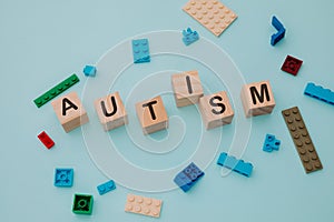 Colorful puzzle and wooden blocks with AUTISM word on a blue background