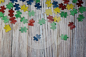 Colorful puzzles on a white wooden background, frame, concept of early childhood autism