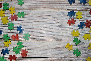 Colorful puzzles on a white wooden background, frame, concept of early childhood autism