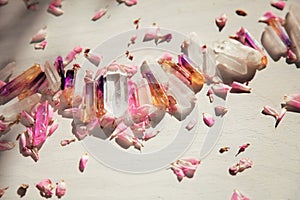 Colorful quartz crystals with pink rose leaves on wooden structure