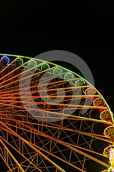 Colorful rainbow-colored ferris wheel at night with copy space