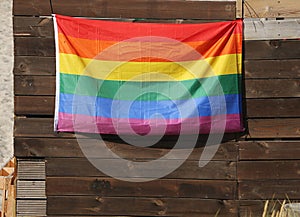 A colorful rainbow flag is hanging on a wooden wall