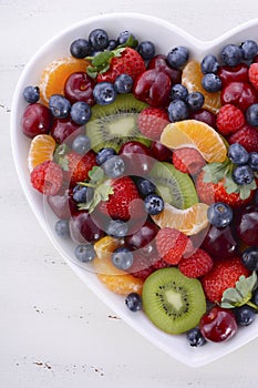 Colorful rainbow fruit in heart shape bowl.