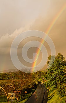 Colorful rainbow in the sky. Storm weather. Cloudy sky. Outgoing sun.