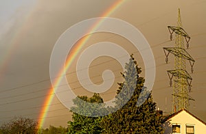 Colorful rainbow in the sky. Storm weather. Cloudy sky. Outgoing sun.