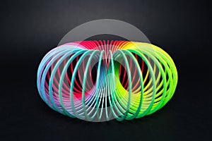 Colorful rainbow spiral toy for play on black background.