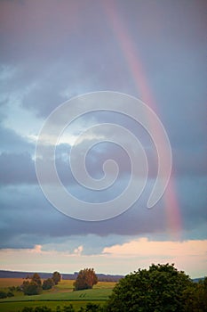 Colorful rainbow after the storm passing over a field of grain on a sunny day, New york state, USA