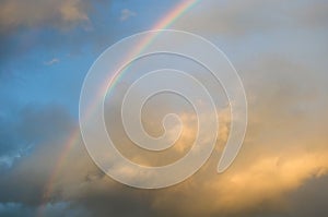 Colorful rainbow in sunset cloudy sky