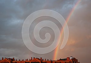 Colorful rainbow in sunset cloudy sky