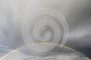 Colorful rainbow symbol of luck on dray gray dramatic cloudy sky