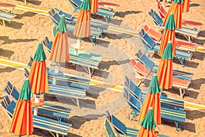Colorful reclining chairs and parasols on a beach seen from above