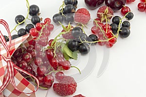 Colorful red berry fruit falling out of decorated box on white