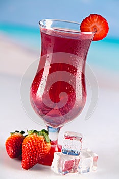 Colorful red cold drink on a beach, summer background