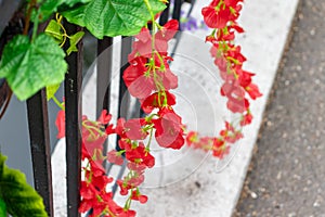 Colorful red delicate beautiful fake artifical flowers decoration on a holiday street open air festival