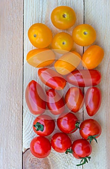 Colorful red, orange and yellow cherry tomatoes on wooden background